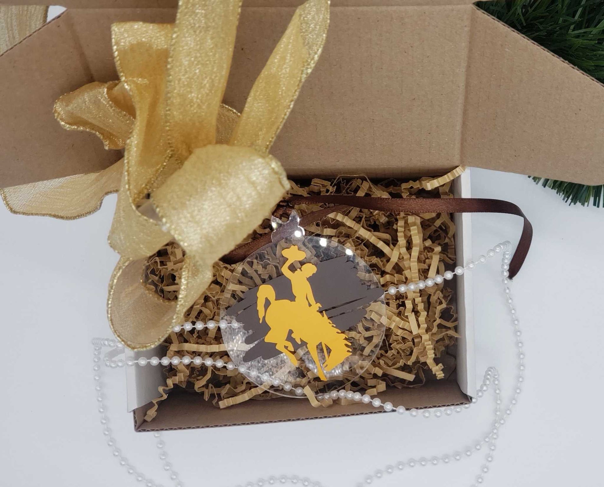 Wyoming Cowboy Ornament with gold bucking horse on brown background, in gift box.