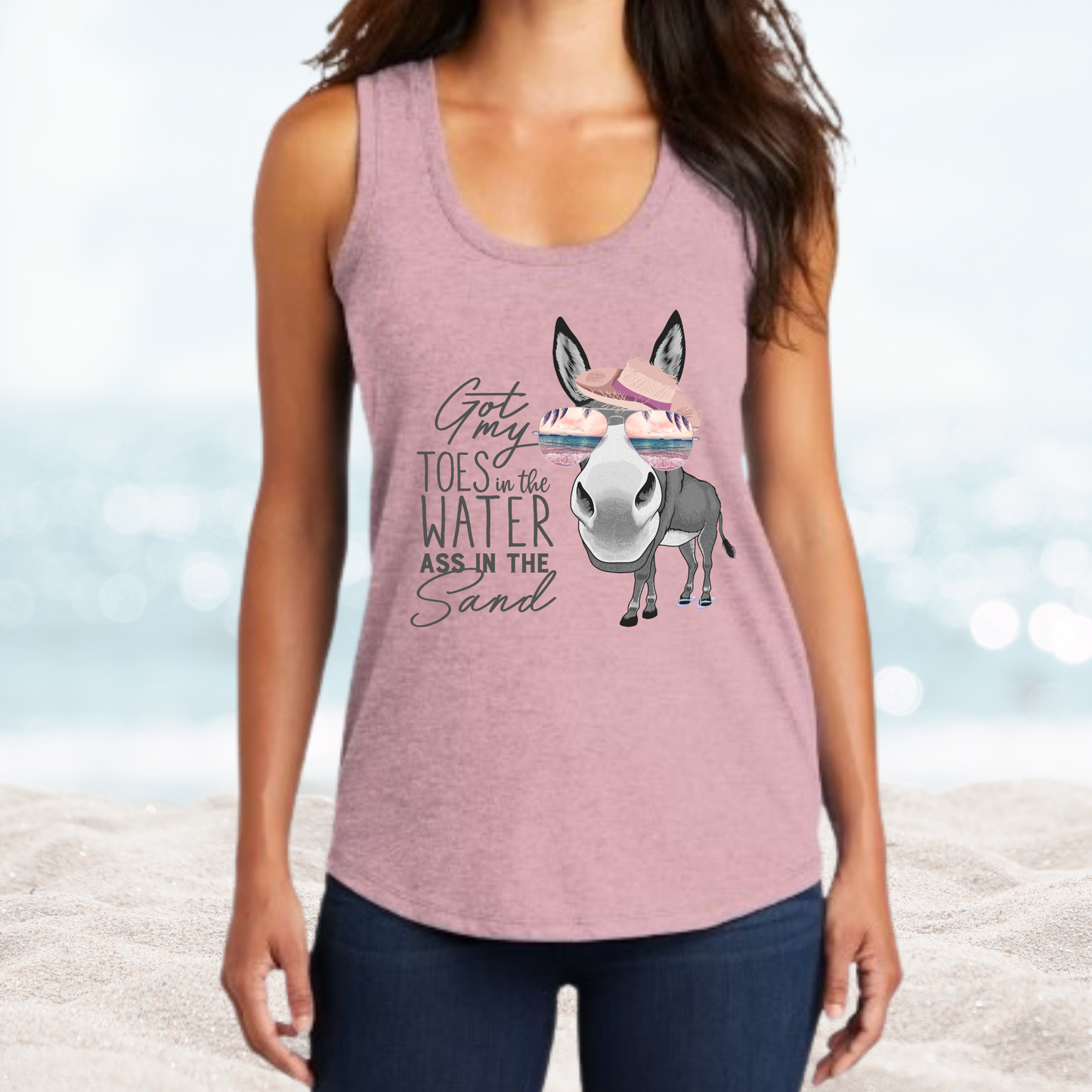 Woman wearing Vacation Toes in the Water Ass in the Sand pink tank top with donkey graphic on beach background