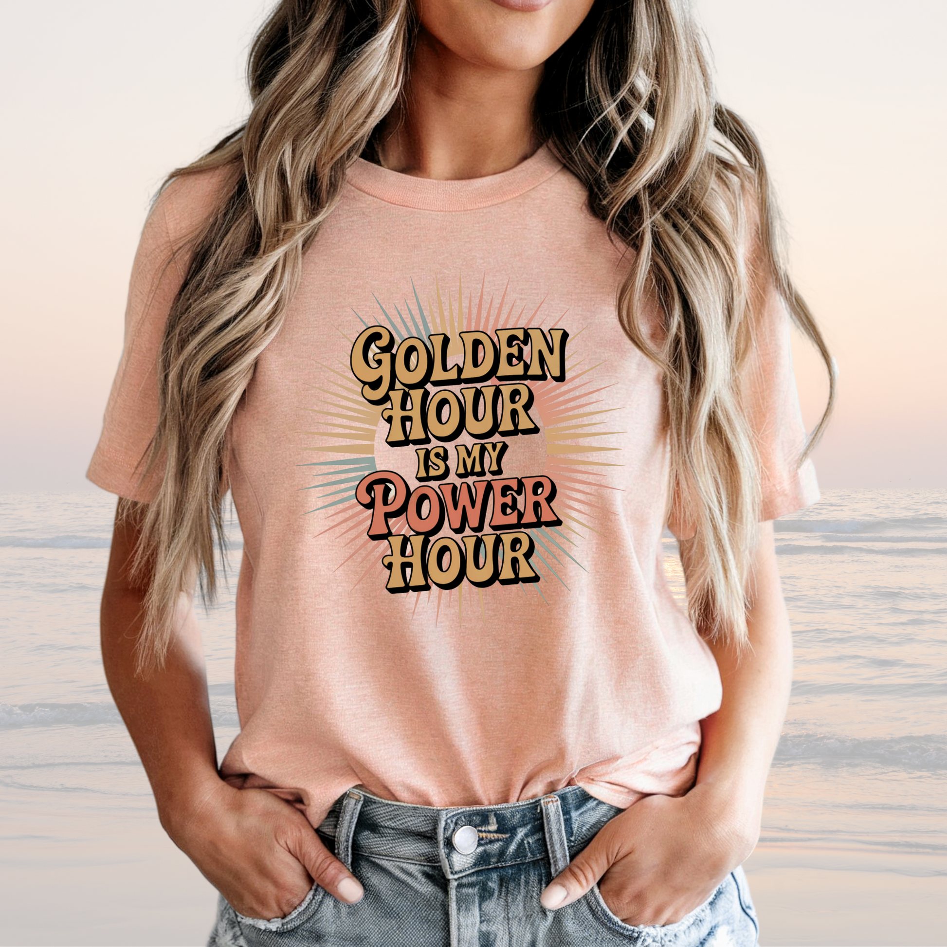 Woman wearing a loose-fitting peach tee with "Golden Hour is My Power Hour" text, styled with casual jeans.