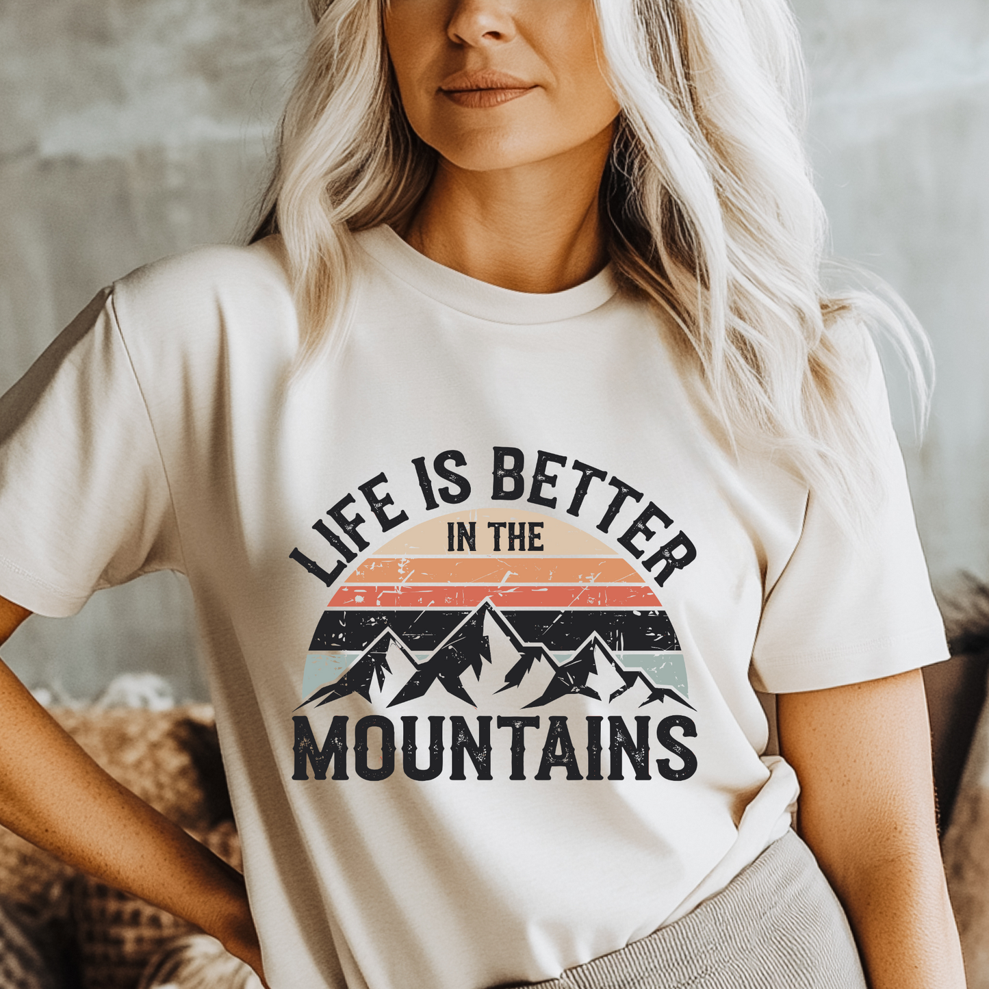 Person wearing a t-shirt with 'Life is Better in the Mountains' graphic design.
