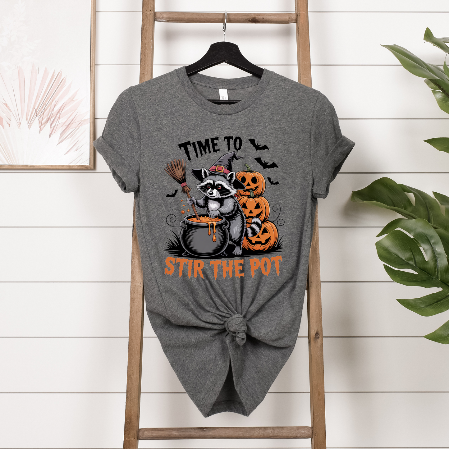 Gray t-shirt with Halloween-themed design featuring a raccoon and pumpkins on a wooden ladder.