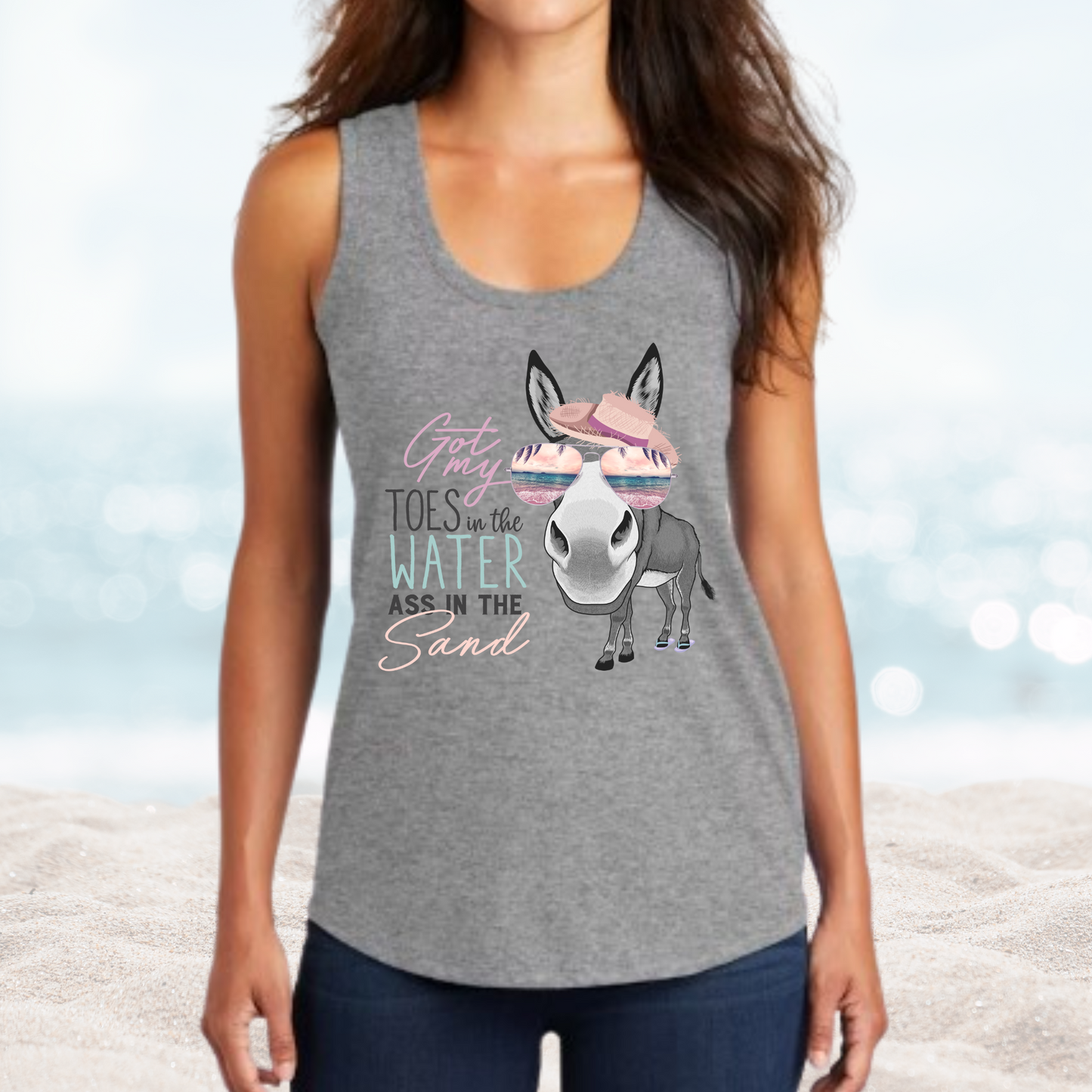 Woman wearing gray tank top with "Vacation Toes in the Water Ass in the Sand" text and donkey graphic with sunglasses and beach hat