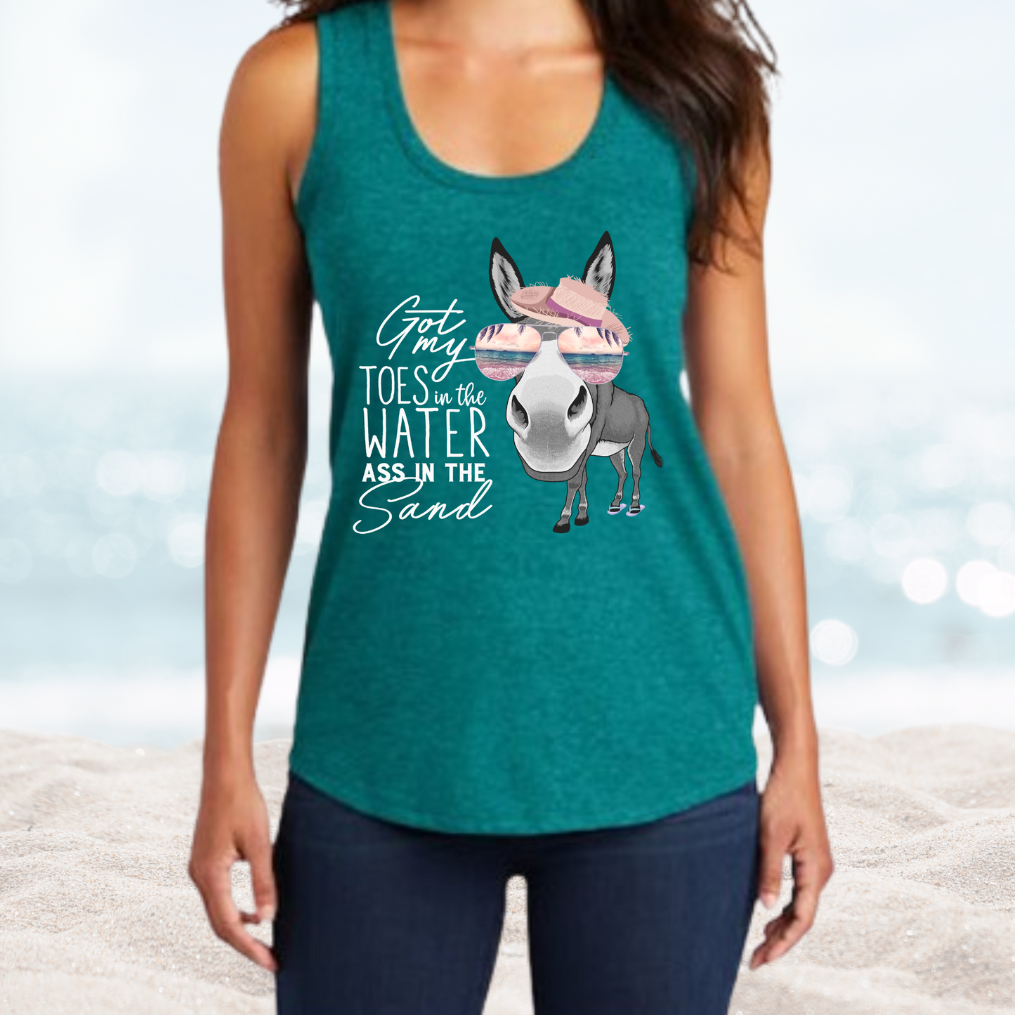 Woman wearing teal Vacation Toes in the Water Ass in the Sand tank top with donkey graphic on beach background