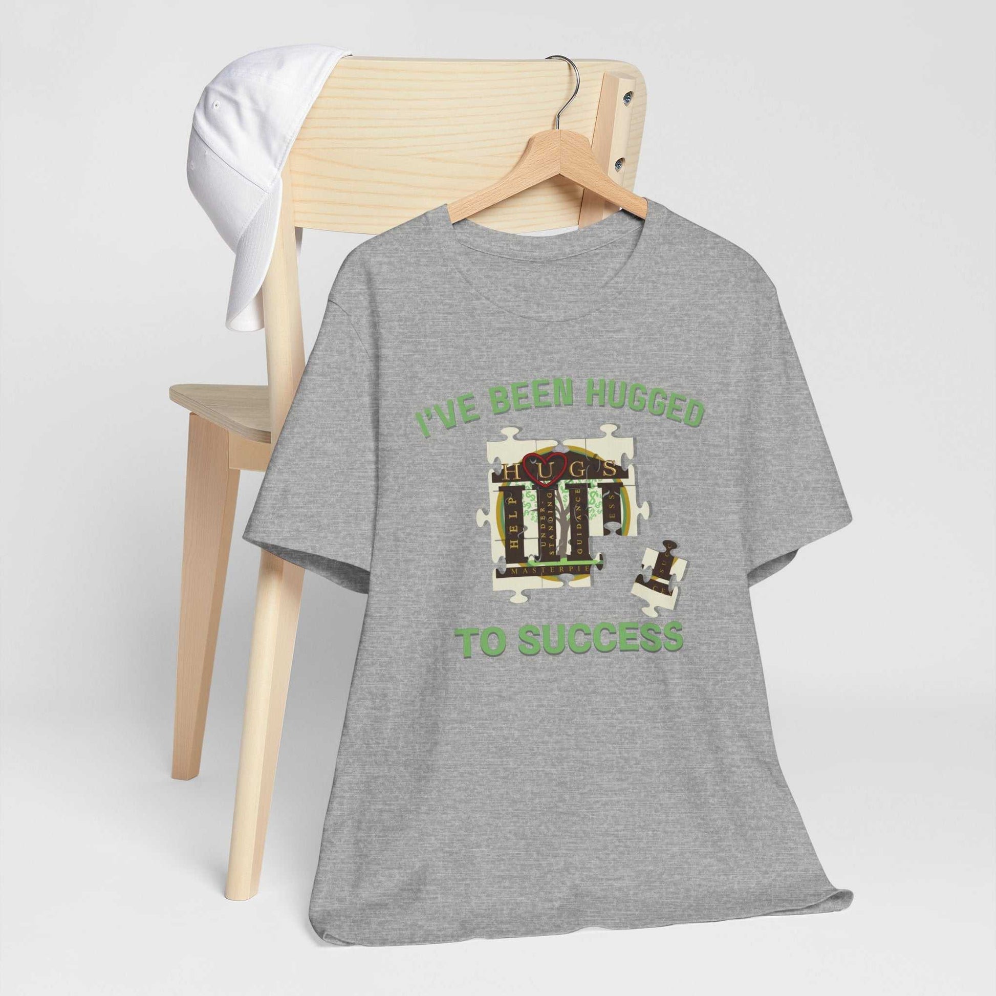 Front view of soft cotton "I've Been Hugged to Success" tee with vintage mech illustration in muted green on natural warm color