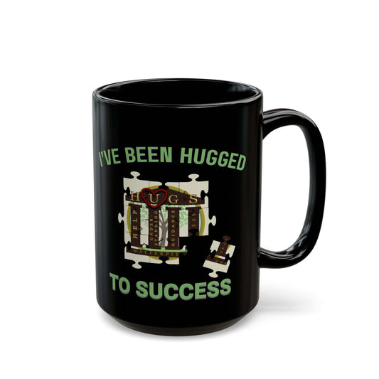 Glossy black coffee mug with mint-green "I've Been Hugged to Success" puzzle design on ceramic surface