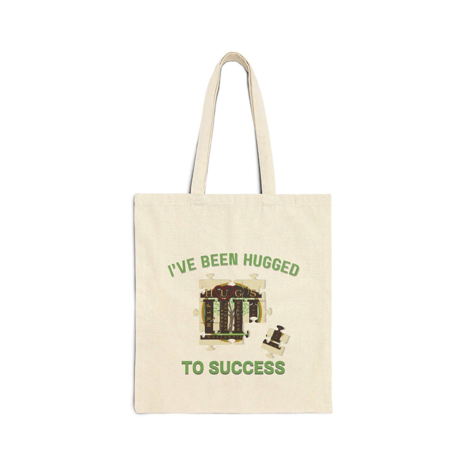 Durable cotton canvas tote bag with "I've Been Hugged to Success" design, sturdy handles, and flat-corner construction in natural color