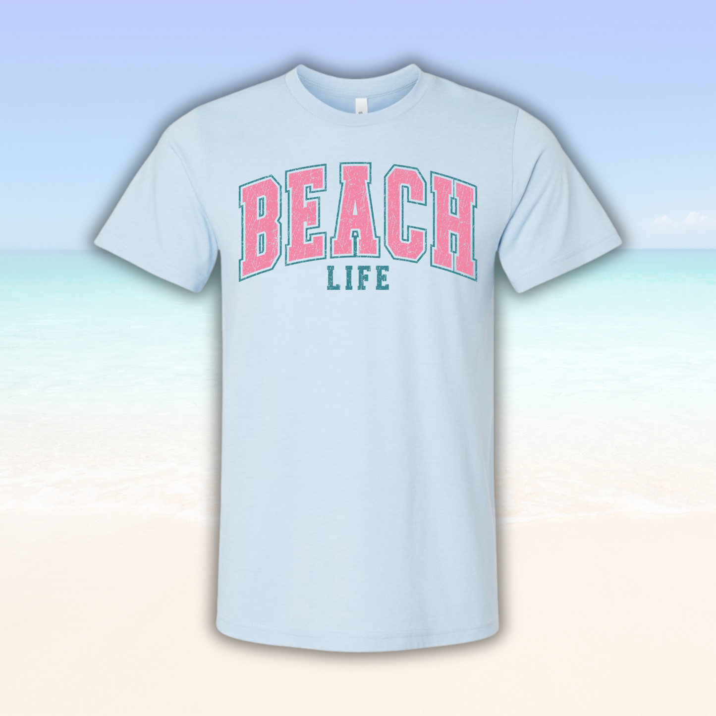 Beach Life Vibe Tee with pink and teal beach-themed design on soft fabric.
