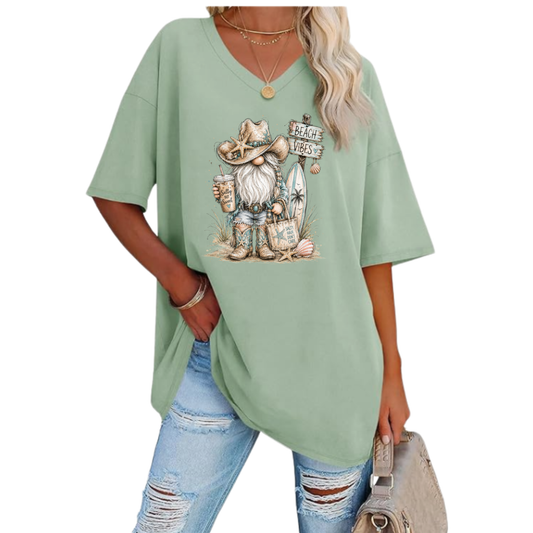 Woman wearing oversized Beach Vibes Gnome V-neck tunic tee with gnome and surfboard design at the beach