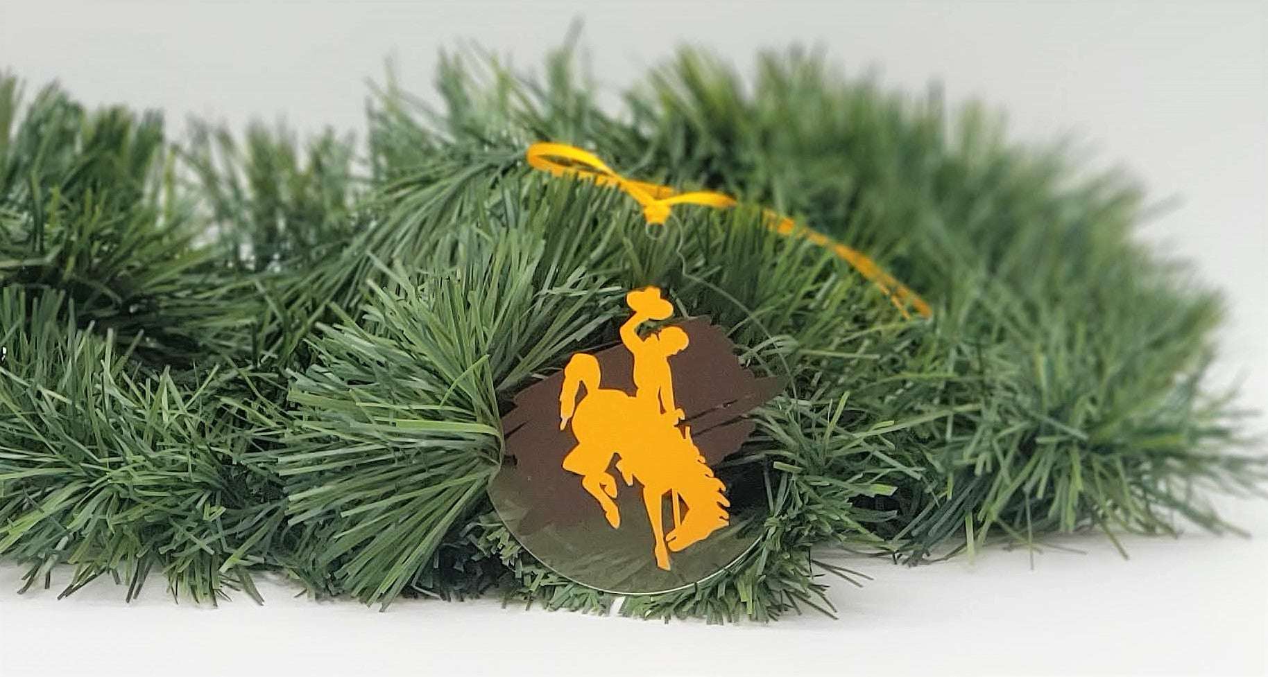Wyoming Cowboy Ornament with gold bucking horse on brown background, University of Wyoming licensed.