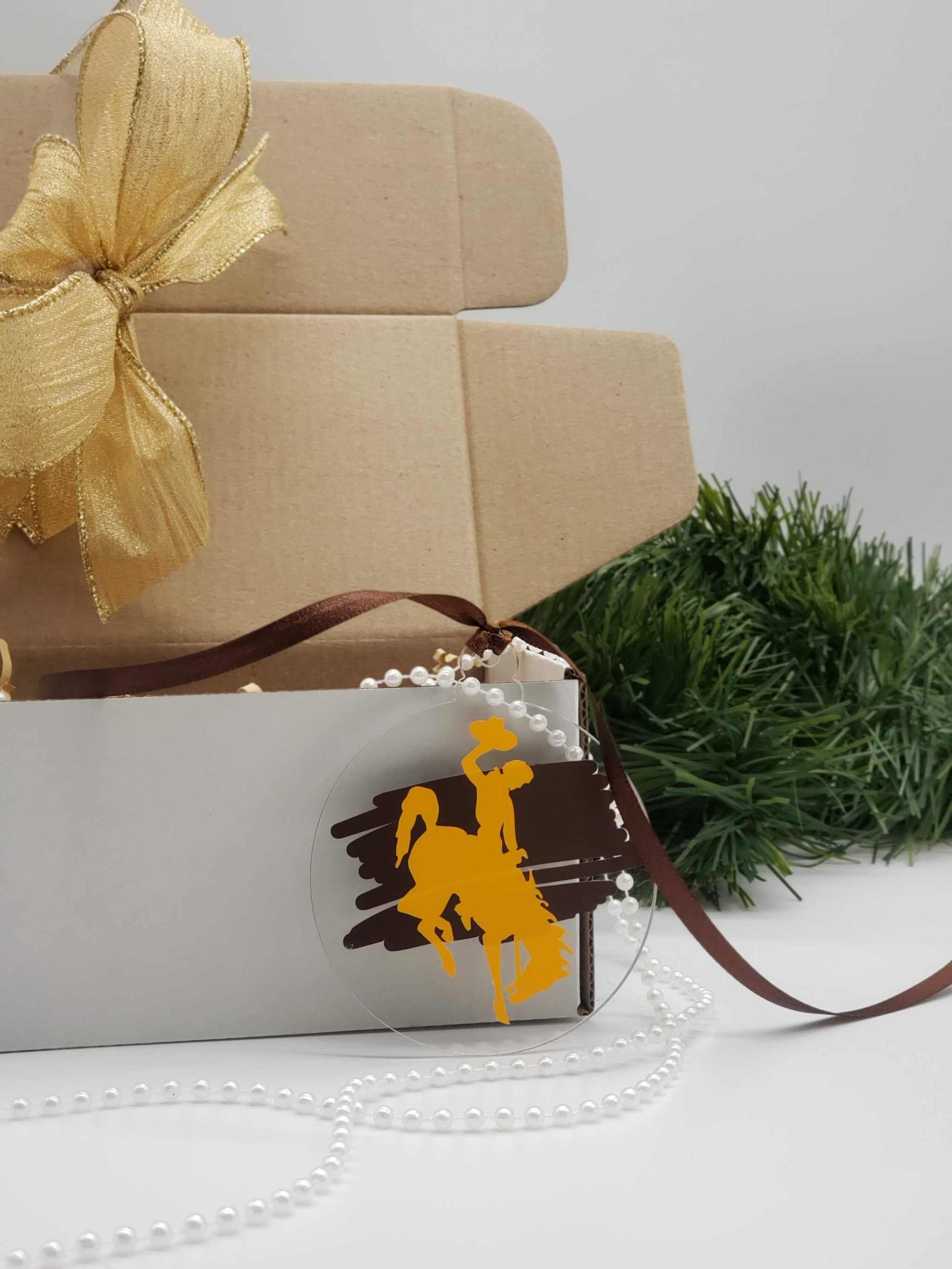 Wyoming Cowboy Ornament with gold bucking horse on brown background, officially licensed by the University of Wyoming.