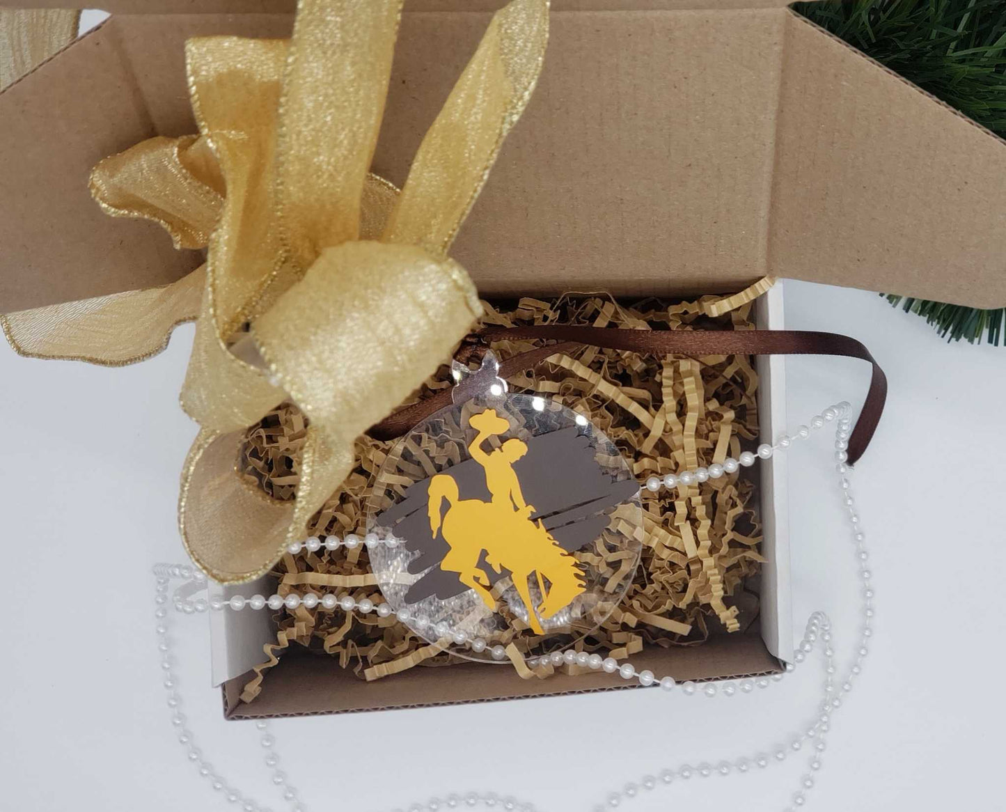 Wyoming Cowboy Ornament with gold bucking horse on brown background, in gift box.