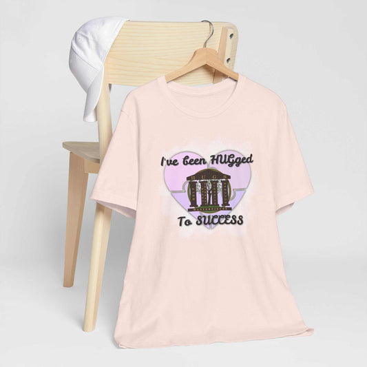 Lightweight pale blush Hugged To Success Tee with vintage storefront and pastel heart graphic