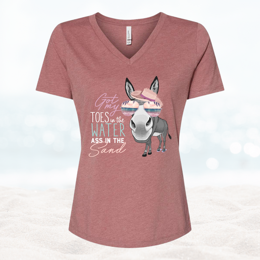 A pink V-neck shirt with a graphic print of a donkey and text 'Get your toes in the water, ass in the sand'.