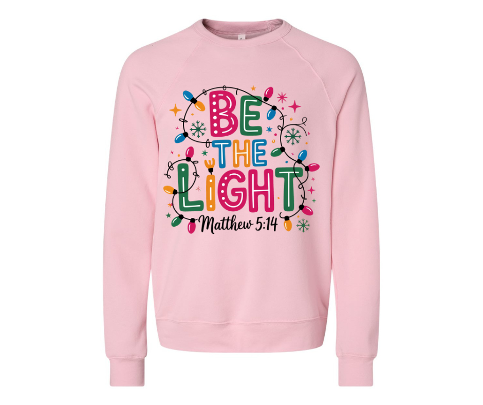 Soft heather pink “Be The Light” sweatshirt. Cozy unisex fit, inspirational Matthew 5:14 design. Perfect for Christmas, gifts, and winter comfort.
