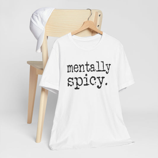 White t-shirt with 'mentally spicy' text on a wooden chair against a white background