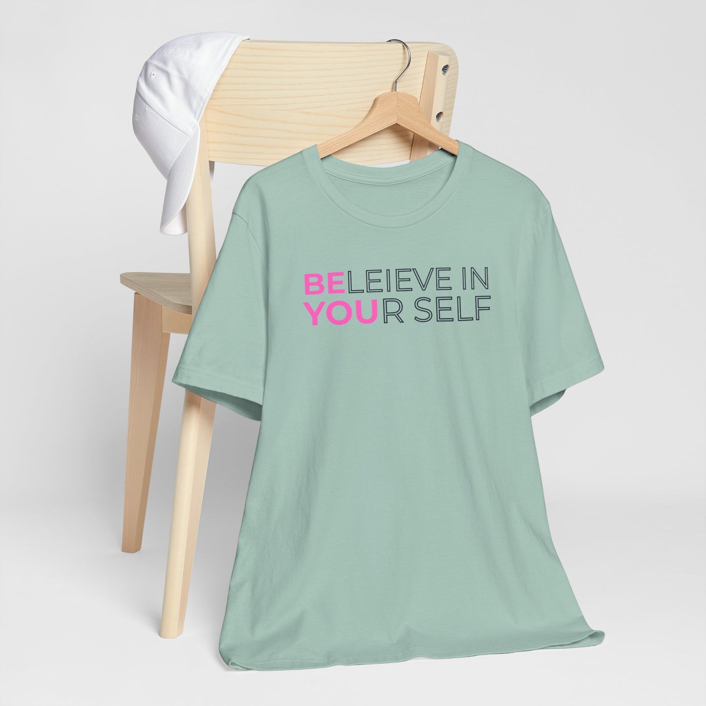 Mint green t-shirt with motivational text on a wooden chair against a white background