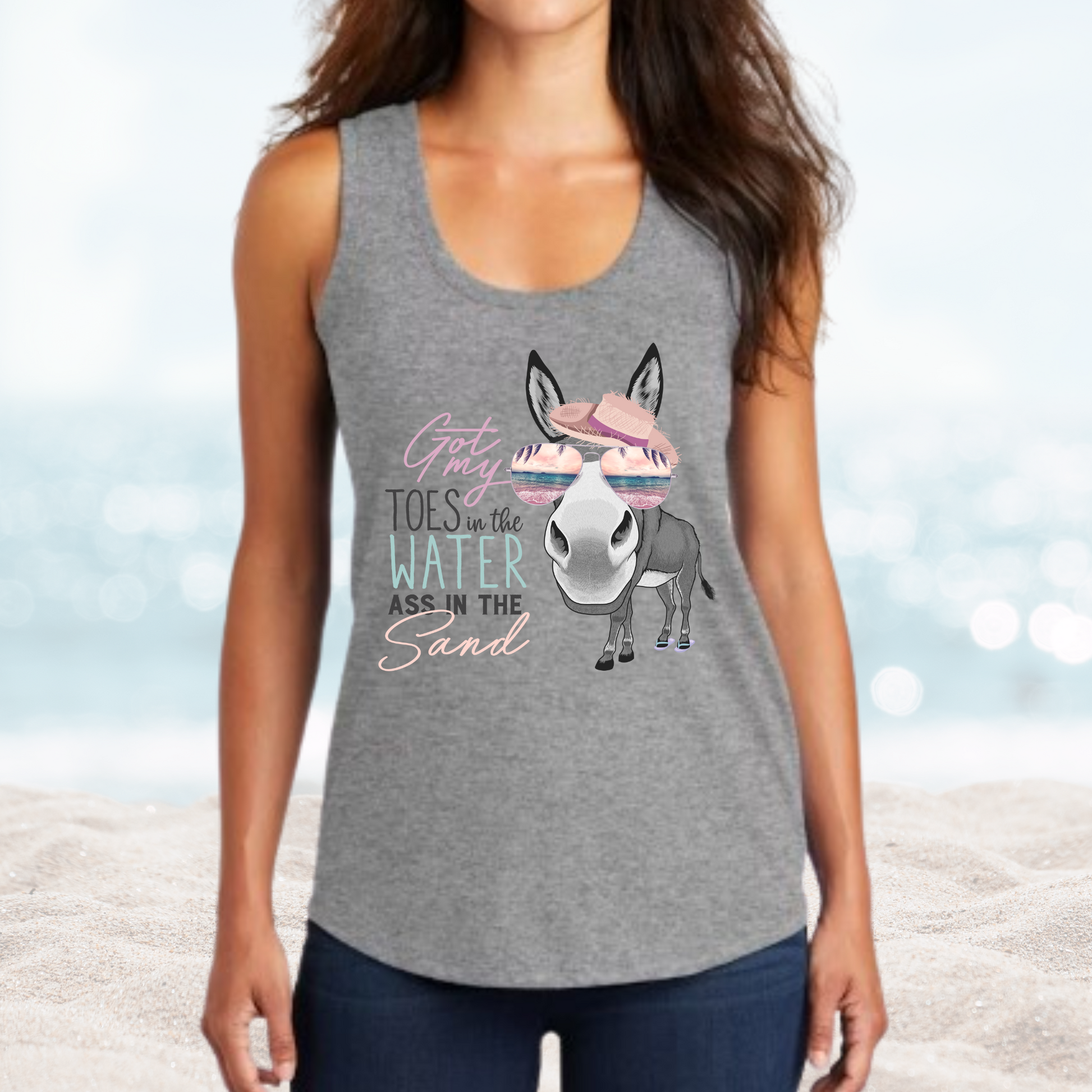 Woman wearing gray tank top with "Vacation Toes in the Water Ass in the Sand" text and donkey graphic with sunglasses and beach hat