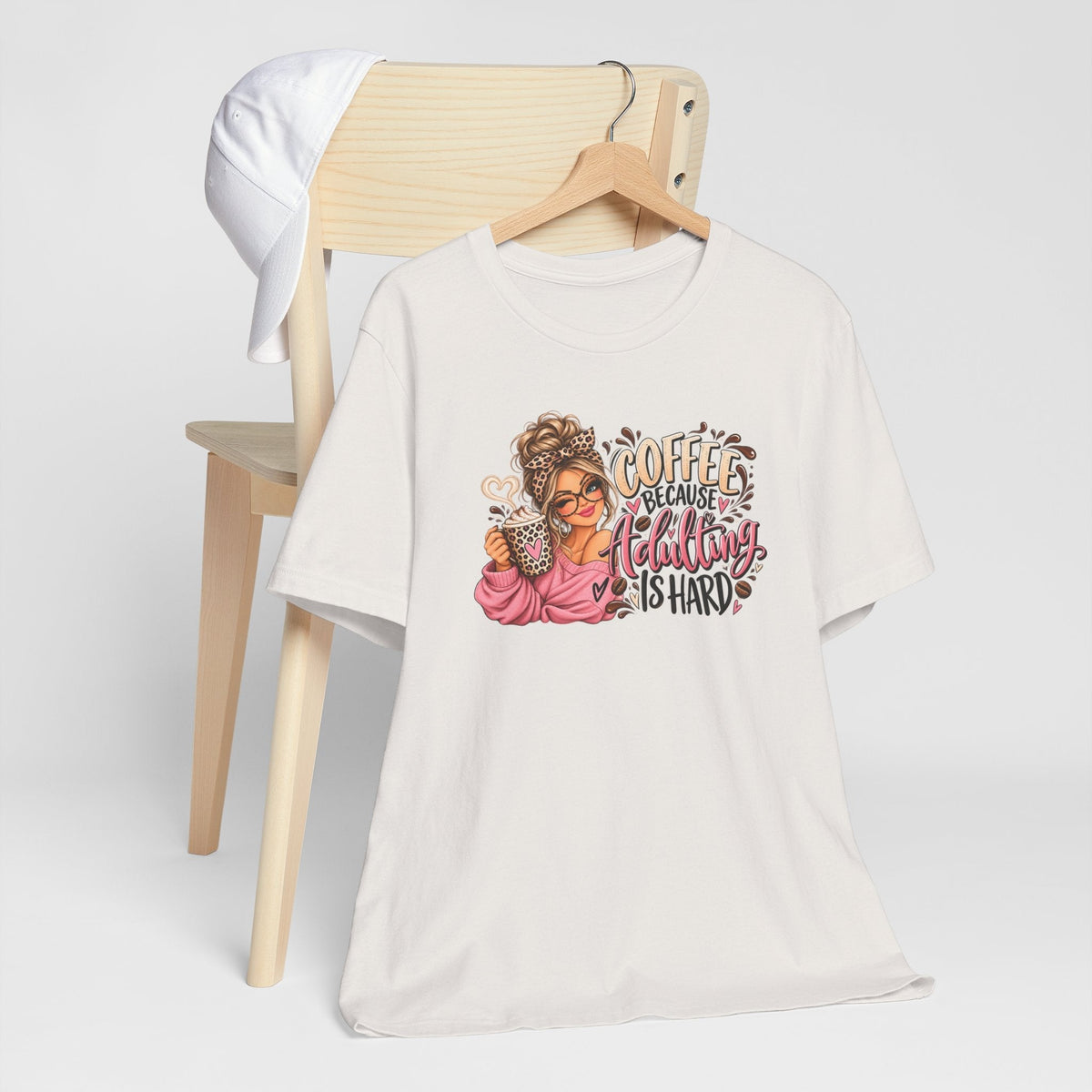 adulting tshirt in off-white cotton with a colorful coffee girl graphic and “Coffee Because Adulting Is Hard” lettering
