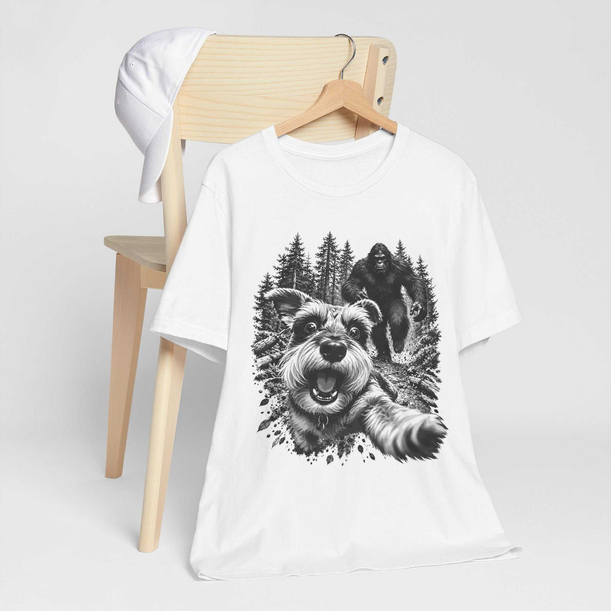 bigfoot shirt in white cotton with a black-and-white graphic of a running dog and Bigfoot among trees
