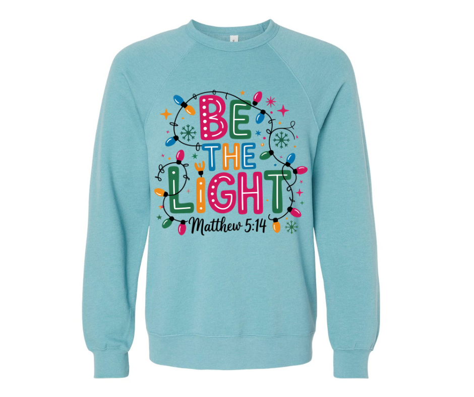 Heather blue lagoon “Be The Light” Christian Christmas sweatshirt, soft unisex crewneck with Matthew 5:14 design.