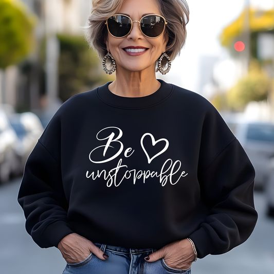 Woman wearing a black sweatshirt with 'Be unstoppable' text on a city street.