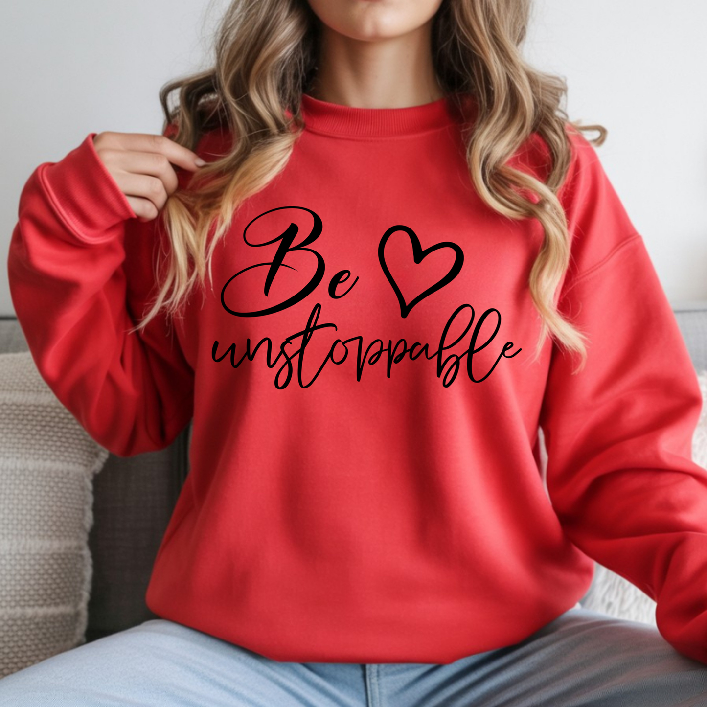 Person wearing a red sweatshirt with 'Be unstoppable' text and heart symbol.
