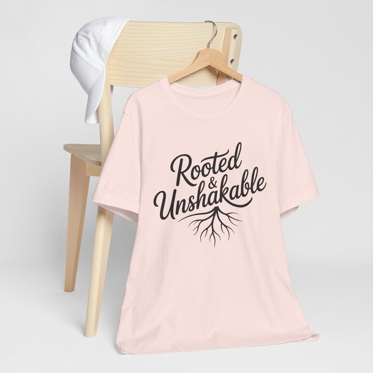 Faith tshirt for ladies in soft pink, with a black “Rooted & Unshakable” script and branching root graphic
