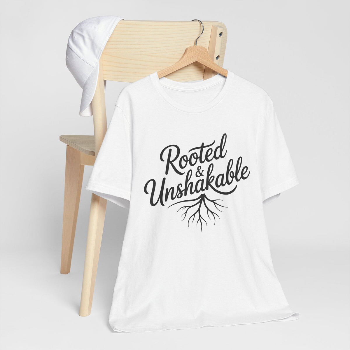 White faith tshirt for ladies with black “Rooted & Unshakable” script and delicate tree root graphic
