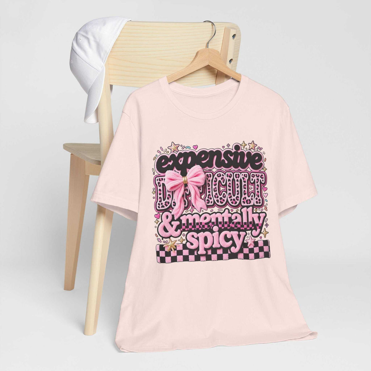 fun womens graphic tee in pale pink with bold leopard-print lettering, a pink bow, stars and checkerboard detail