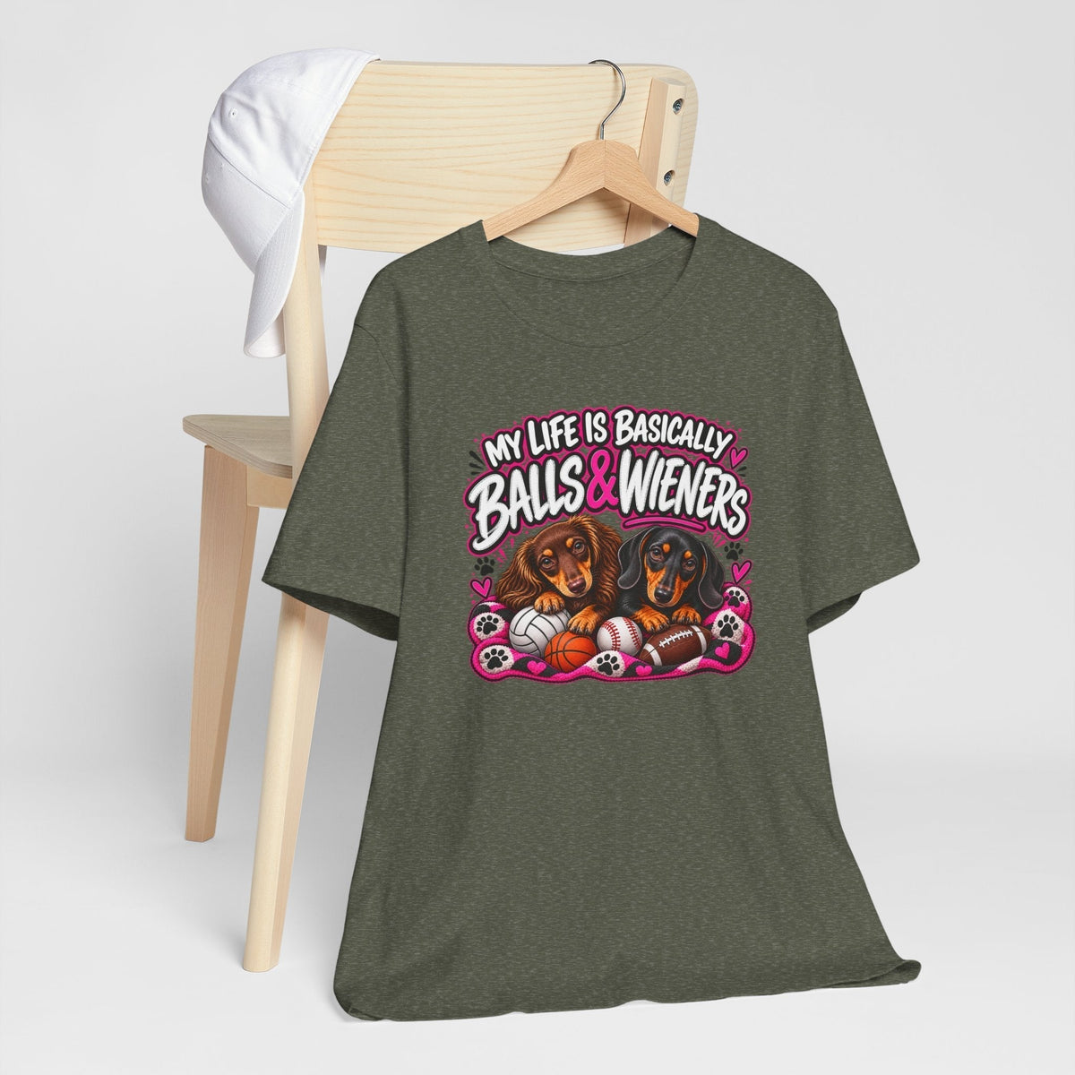 funny dachshund graphic tee in dark olive cotton with a bright pink and white design, two dogs and sports balls