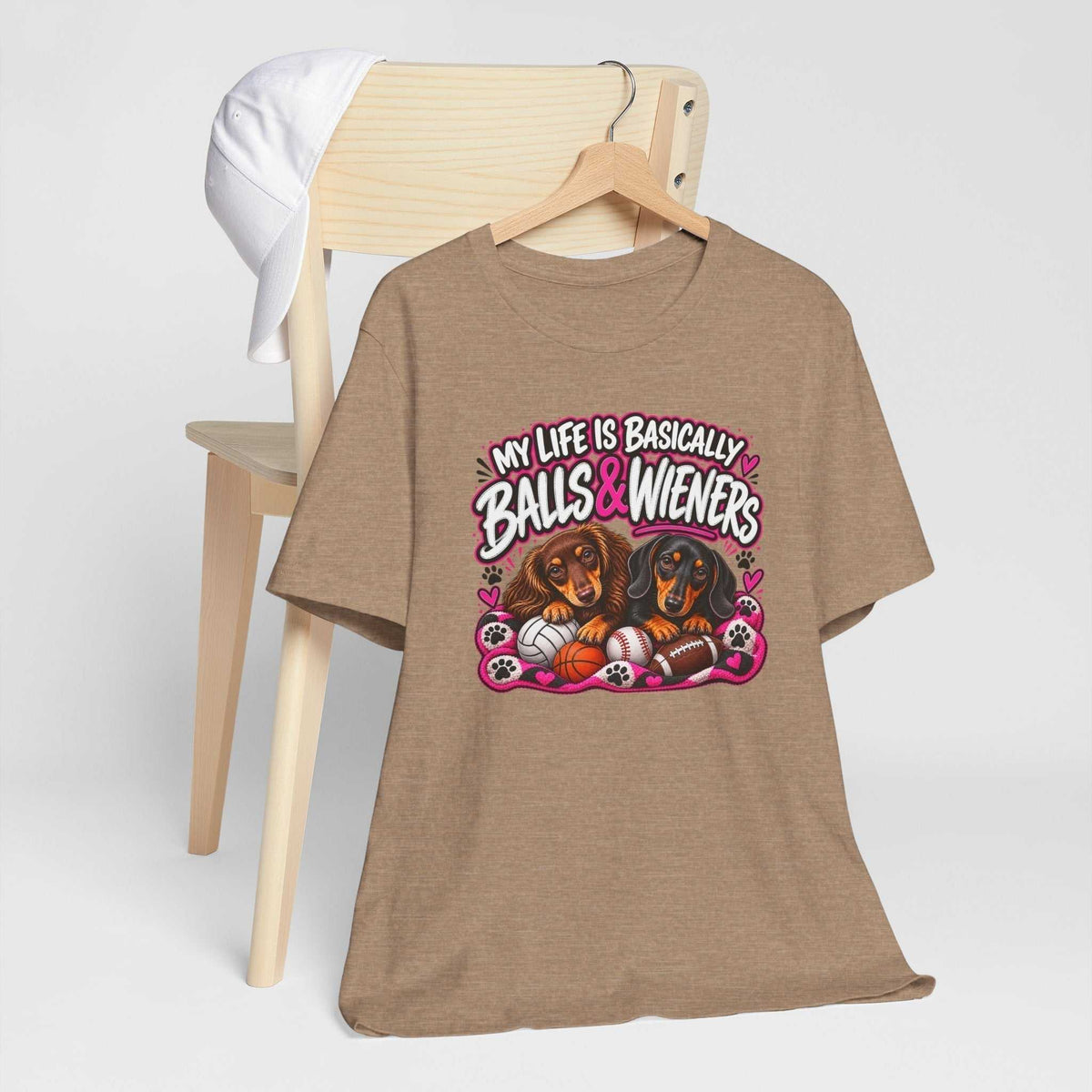 Funny dachshund graphic tee in tan cotton with a colorful design of two dachshunds, sports balls and playful lettering