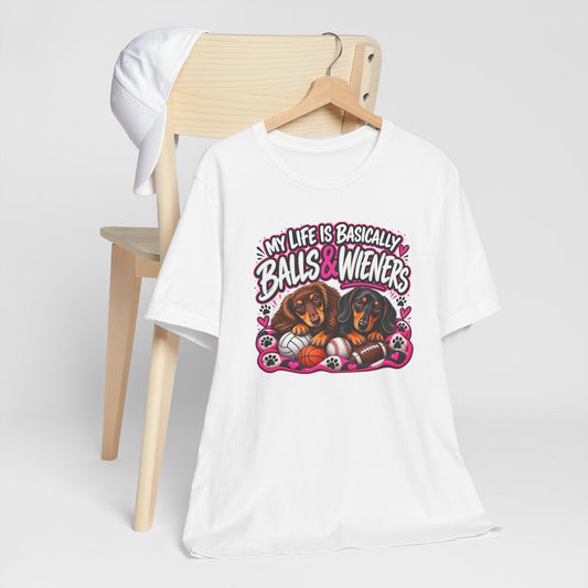 funny dachshund graphic tee in white cotton with pink, black and brown print of two dachshunds, sports balls and playful lettering