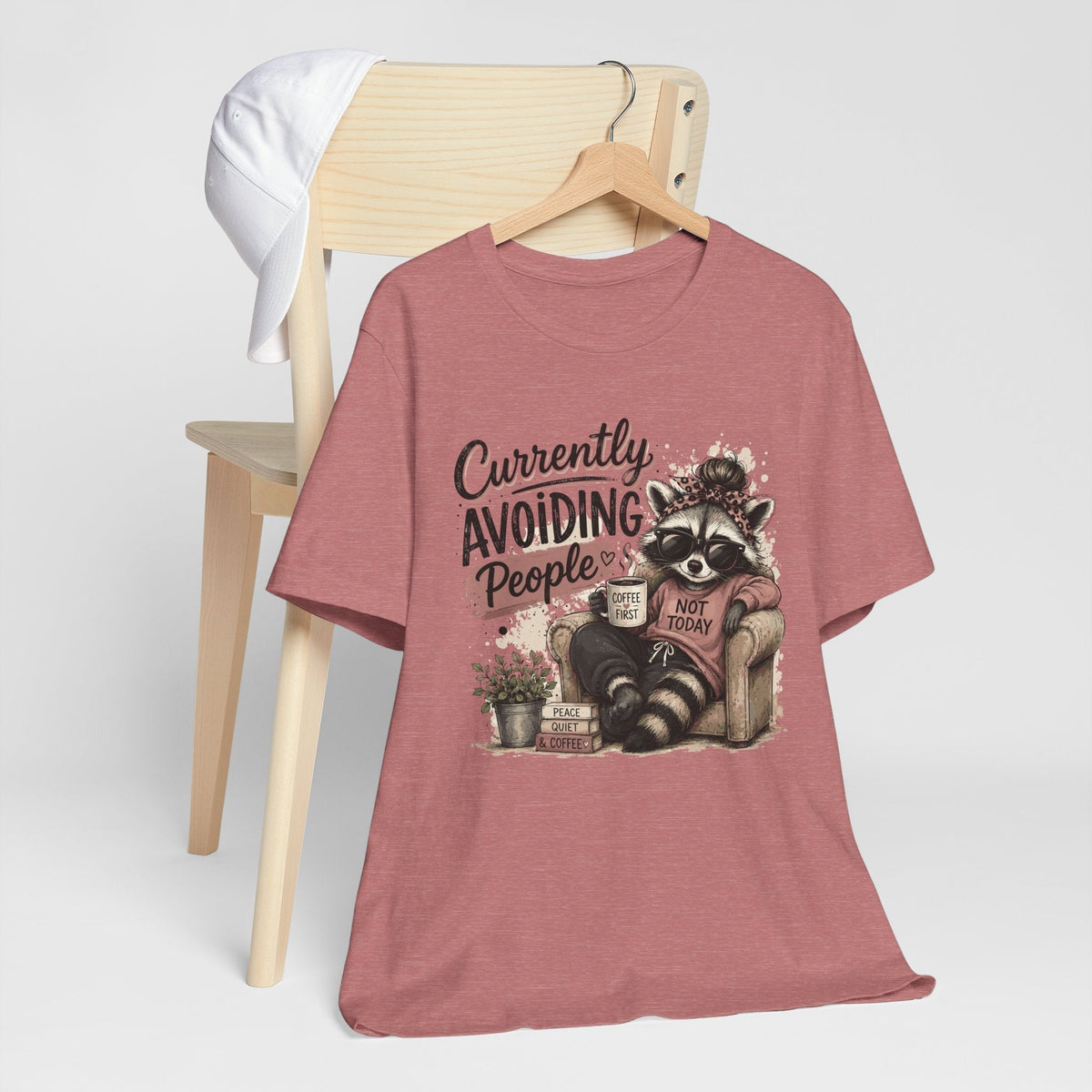 funny tee shirt in dusty rose with a raccoon in sunglasses holding coffee beside a humorous people-avoiding slogan
