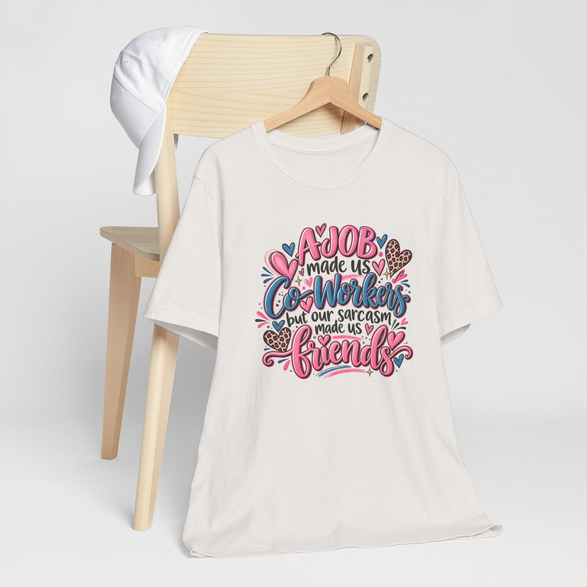 T-shirt in white cotton with colorful floral lettering, a sarcastic coworkers-to-friends message, and hearts; gift ideas for coworkers