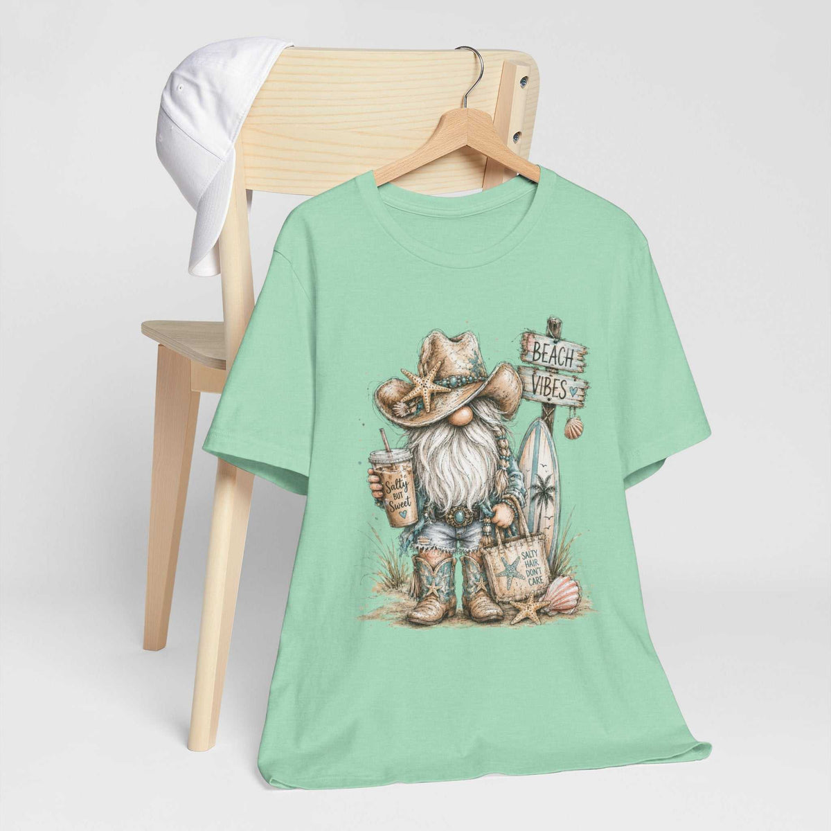 gnome t shirts in mint green cotton with a watercolor beach gnome wearing a starfish-decorated hat beside a beach sign