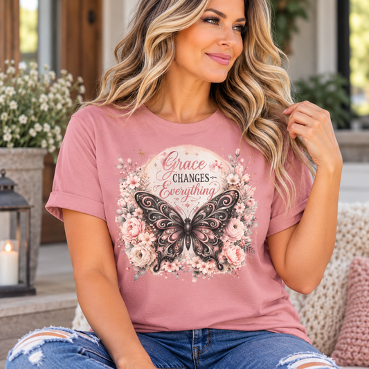 Women's pink cotton T-shirt with an ornate black butterfly, blush flowers, and “Grace Changes Everything” lettering; grace change everything
