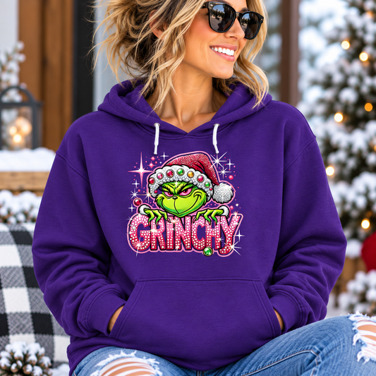Grinchy Christmas Hoodie in purple with a colorful Grinch in a Santa hat and sparkling holiday lettering