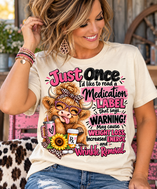 highland cow tshirt women's cream short-sleeve tee with colorful medication-label graphic, glasses-wearing cow and pink lettering