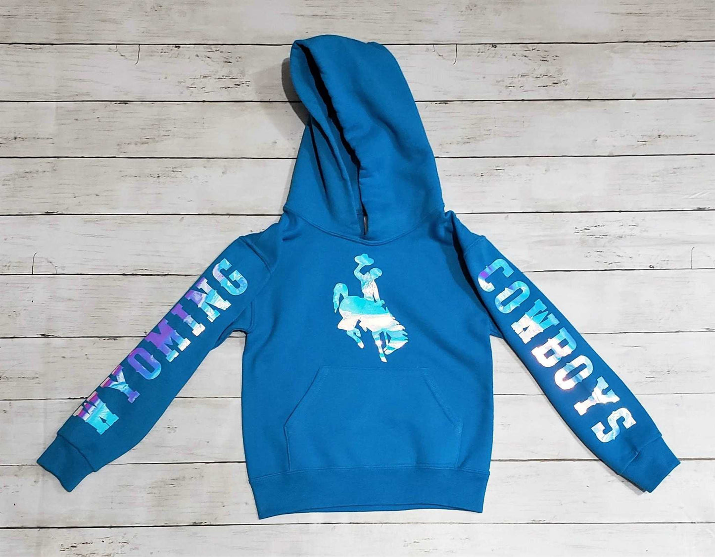 Wyoming Cowboy Youth Hoodie with holographic logo, California Blue color, featuring "WYOMING" and "COWBOYS" on sleeves, University of Wyoming licensed.