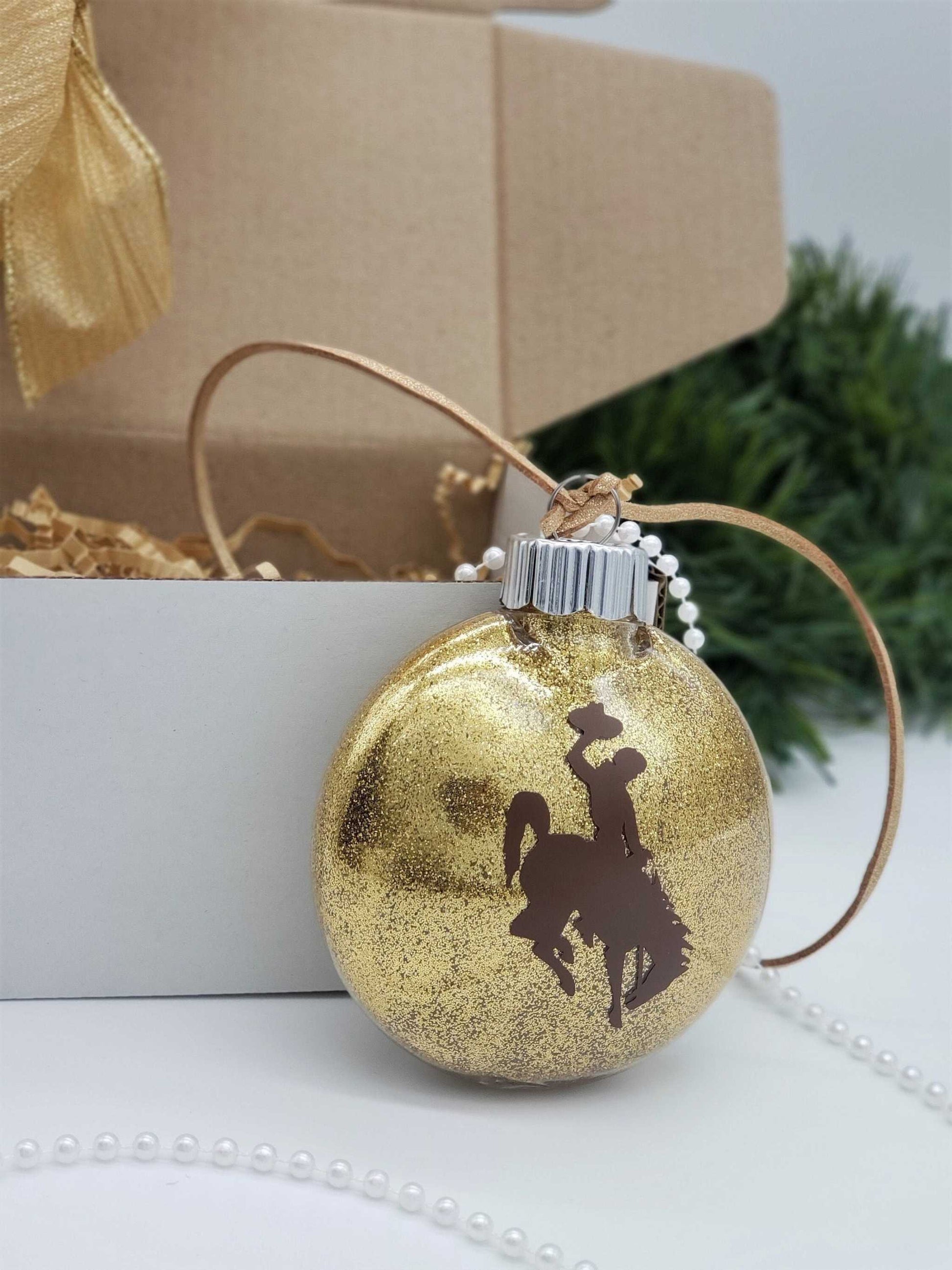 Wyoming Cowboy Ornament with gold glitter and brown steamboat design, University of Wyoming themed.