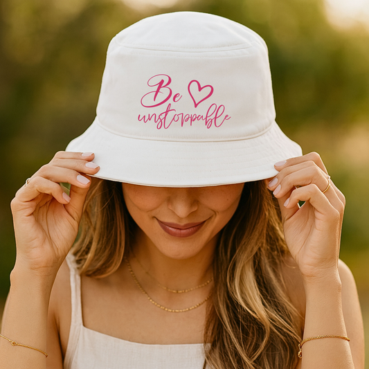 Inspirational hat in white cotton twill with pink “Be unstoppable” script embroidery and a heart on a bucket-style brim