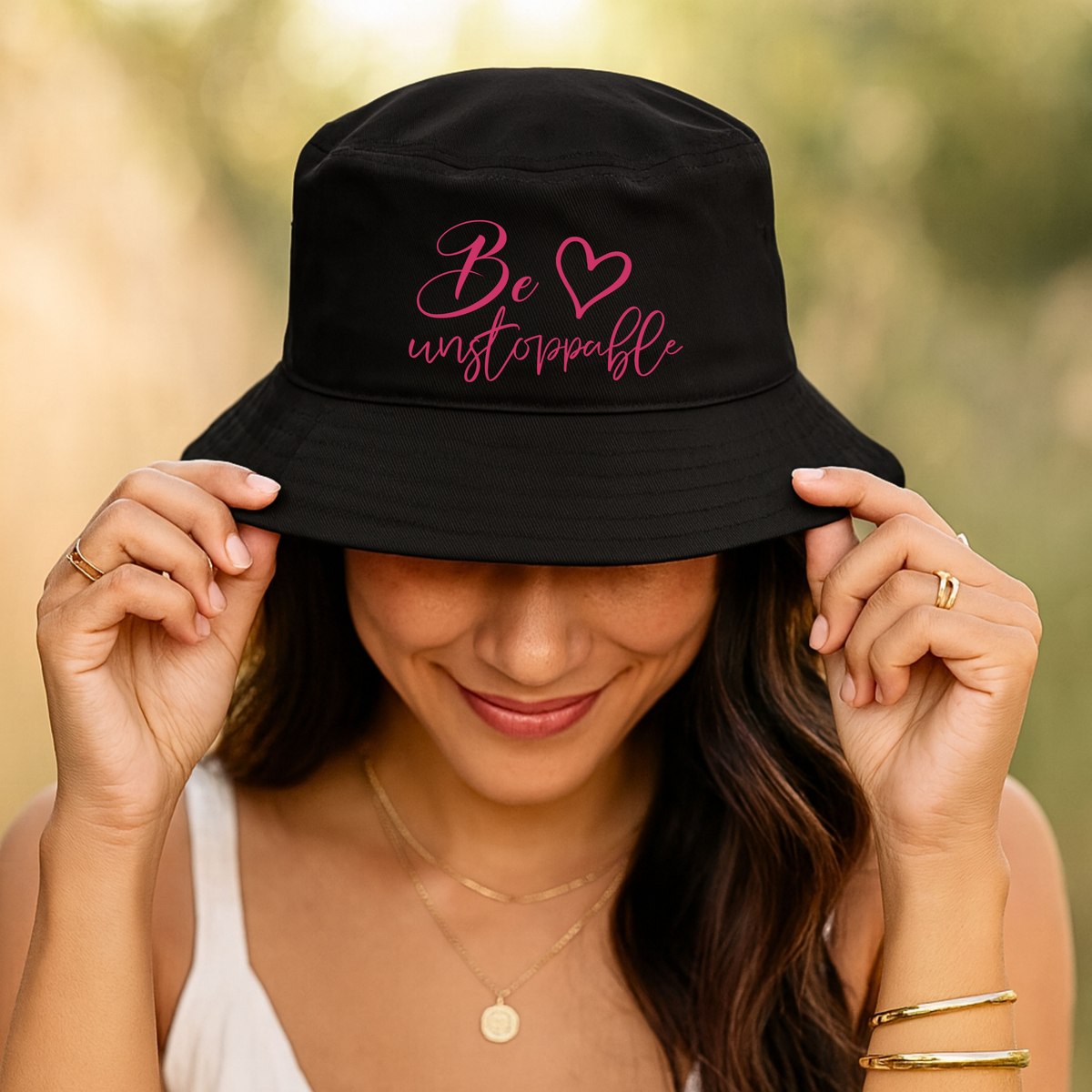 Black cotton twill inspirational hat with bright pink “Be Unstoppable” script embroidery and a wide stitched brim