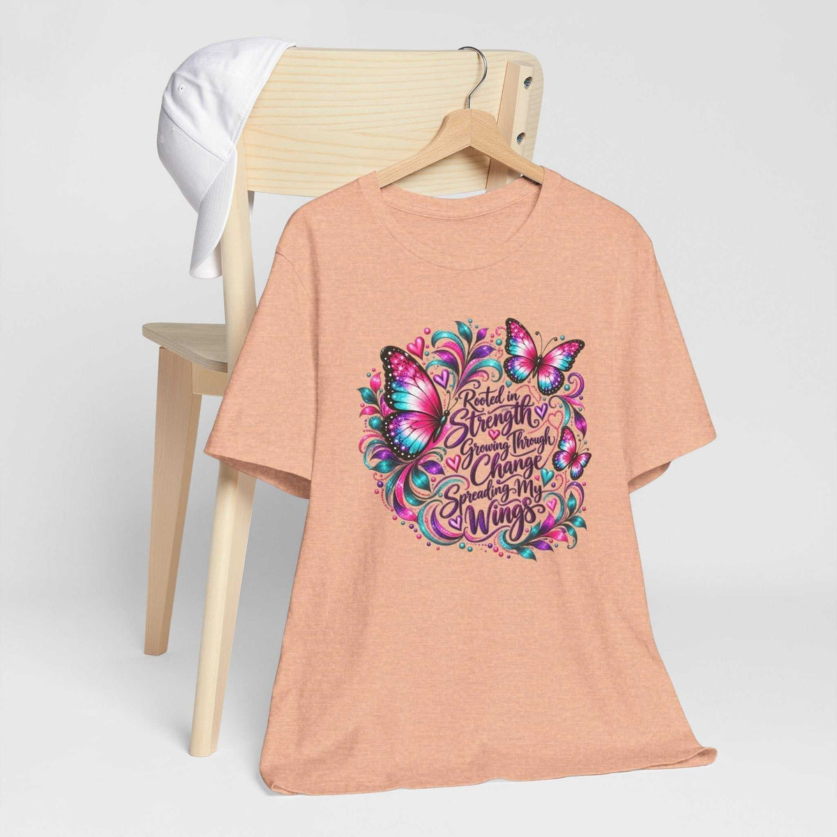 Inspirational tshirt design on a peach heather tee, featuring vibrant pink and teal butterflies and a growth message