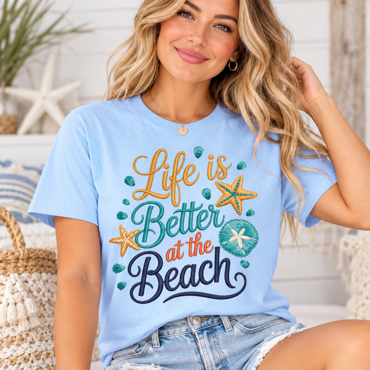 T-shirt in light blue cotton with life is better at the beach lettering in gold, teal and navy, seashells and starfish