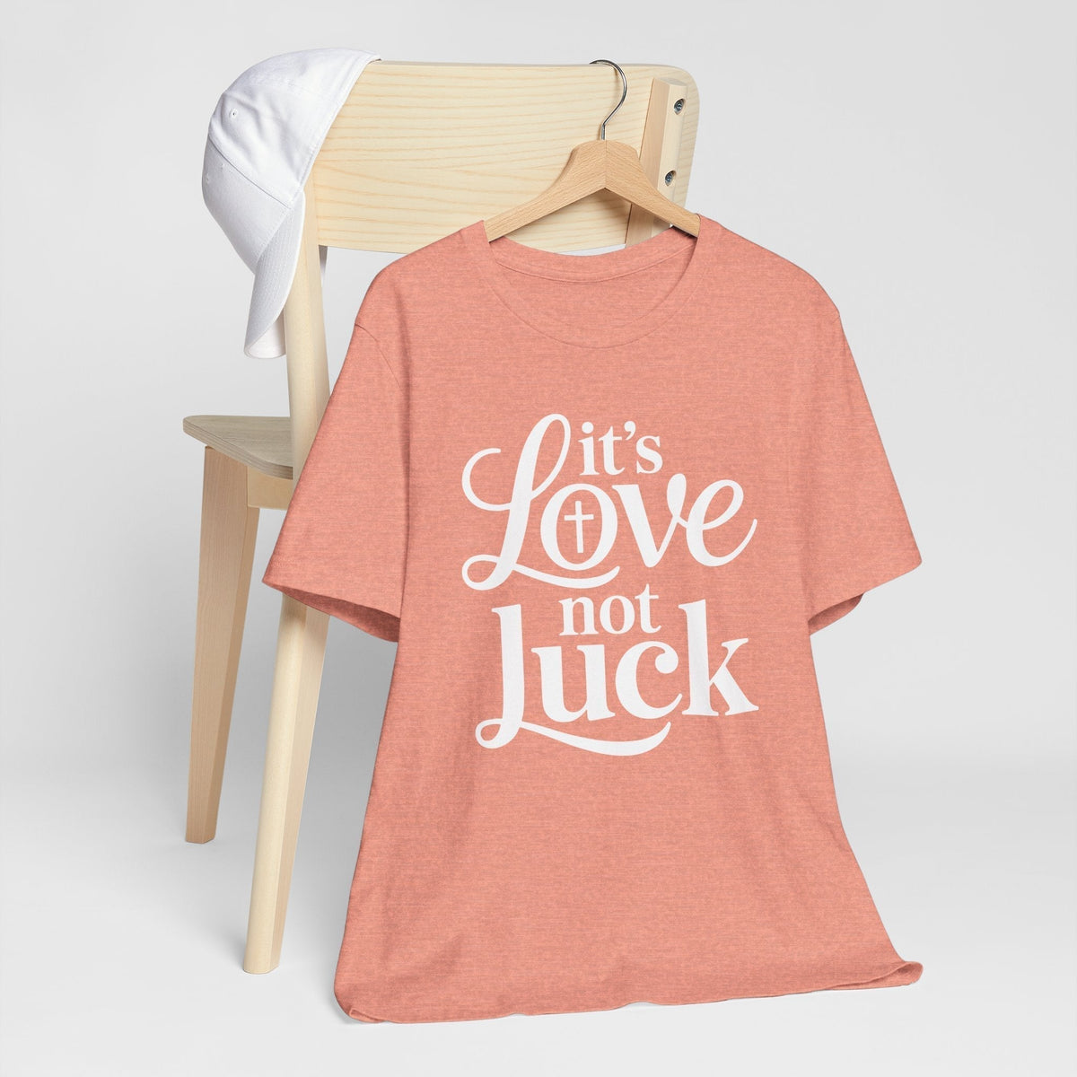 love in faith shirt in dusty coral with white script and serif lettering reading “It’s Love not Luck”