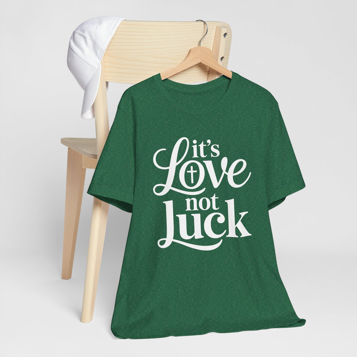 love in faith shirt, a forest green cotton graphic tee with white script and serif lettering reading “It’s Love Not Luck”