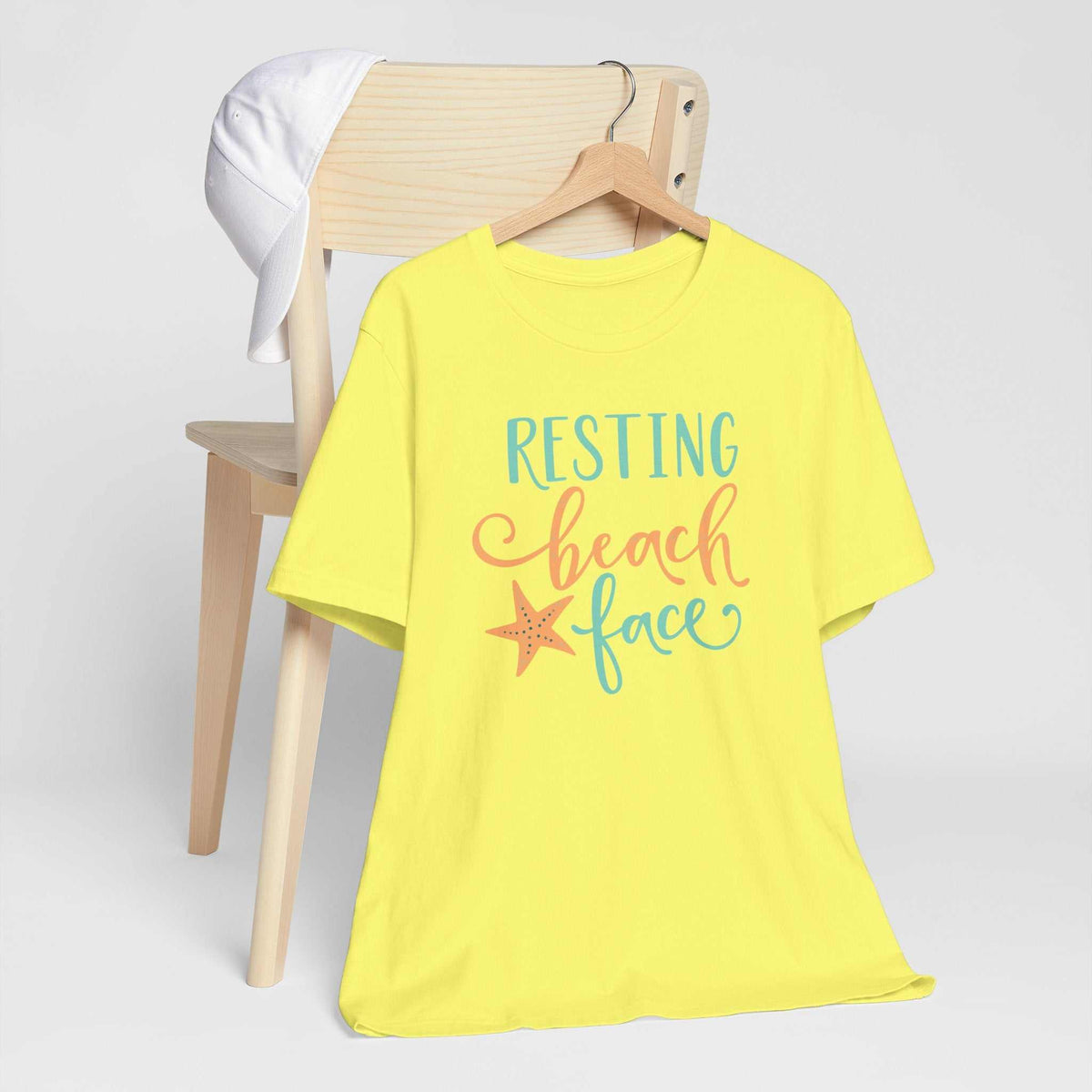 Resting Beach Face graphic T-shirt in bright yellow cotton, with turquoise and coral lettering and a starfish design