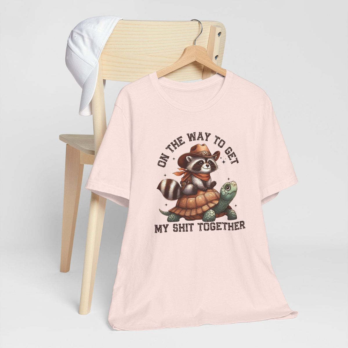 Sassy tee shirt in pale pink with a cowboy raccoon riding a turtle and humorous western lettering