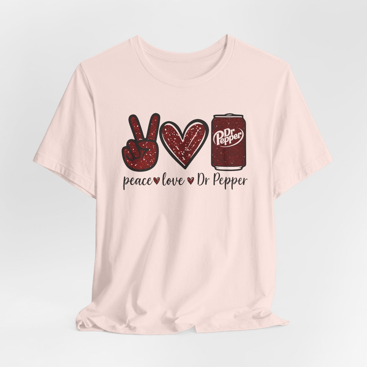 Soda lover T-shirt in pale pink cotton with a red peace sign, heart, Dr Pepper can, and playful lettering