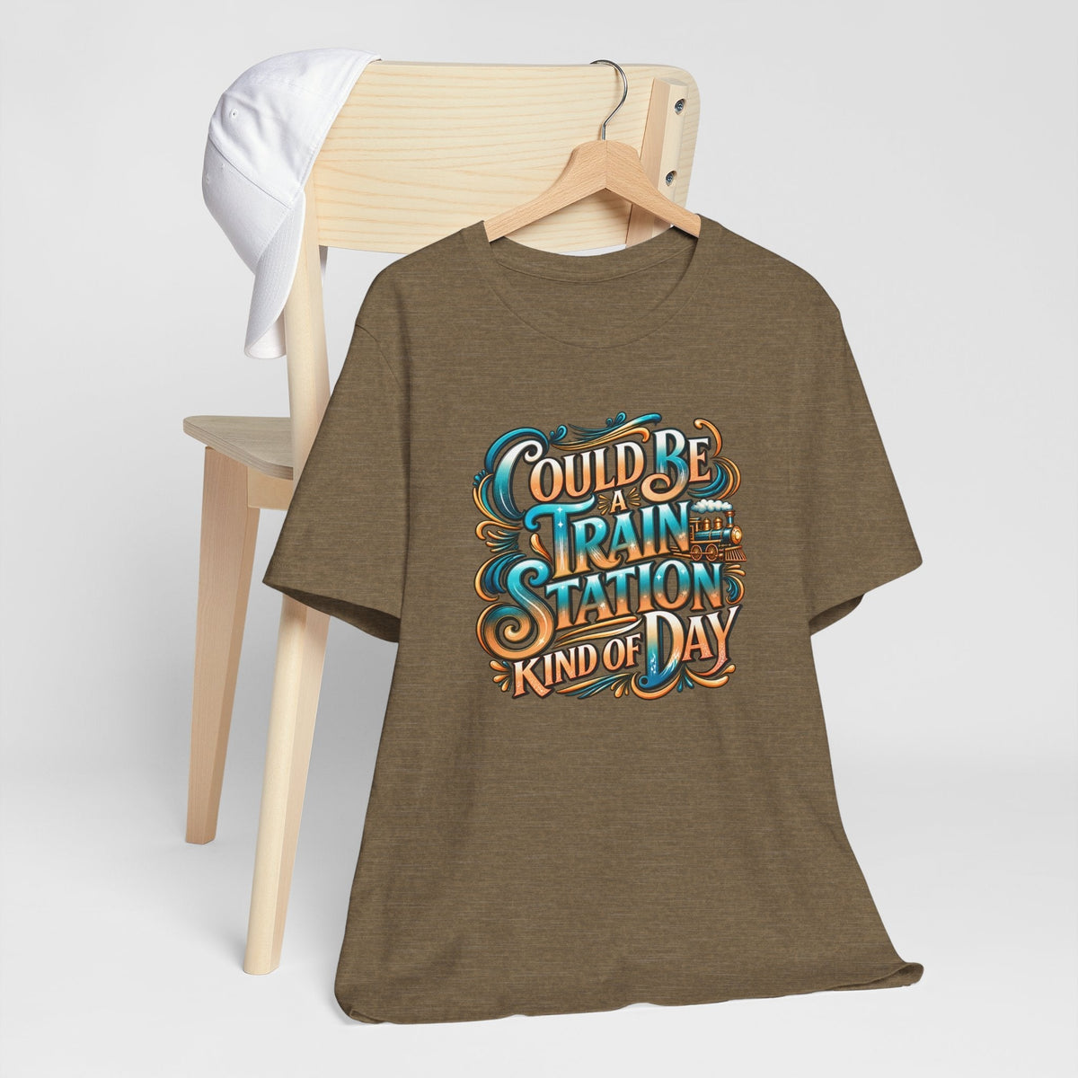 T-shirt with a brown heathered fabric and ornate turquoise, orange, and cream lettering reading “Could Be a Train Station Kind of Day”; train station kinda day
